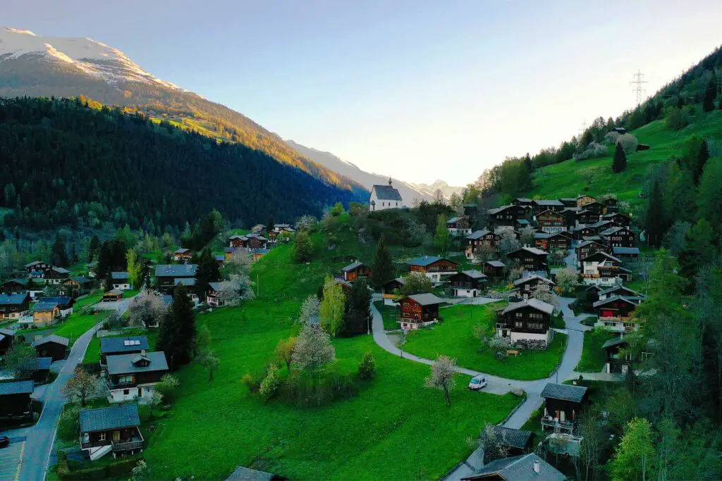 Drohnenaufnahme des Walliser Bergdorfes Mühlebach bei Sonnenaufgang.